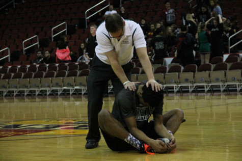 Assistant coach Denis McDonald helps Junior Neico Green stretch before the game against the Waukee Warriors.