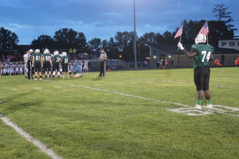 Senior Calvonta Stallings holds u[ two flags while the captains meet in the middle of the field. 